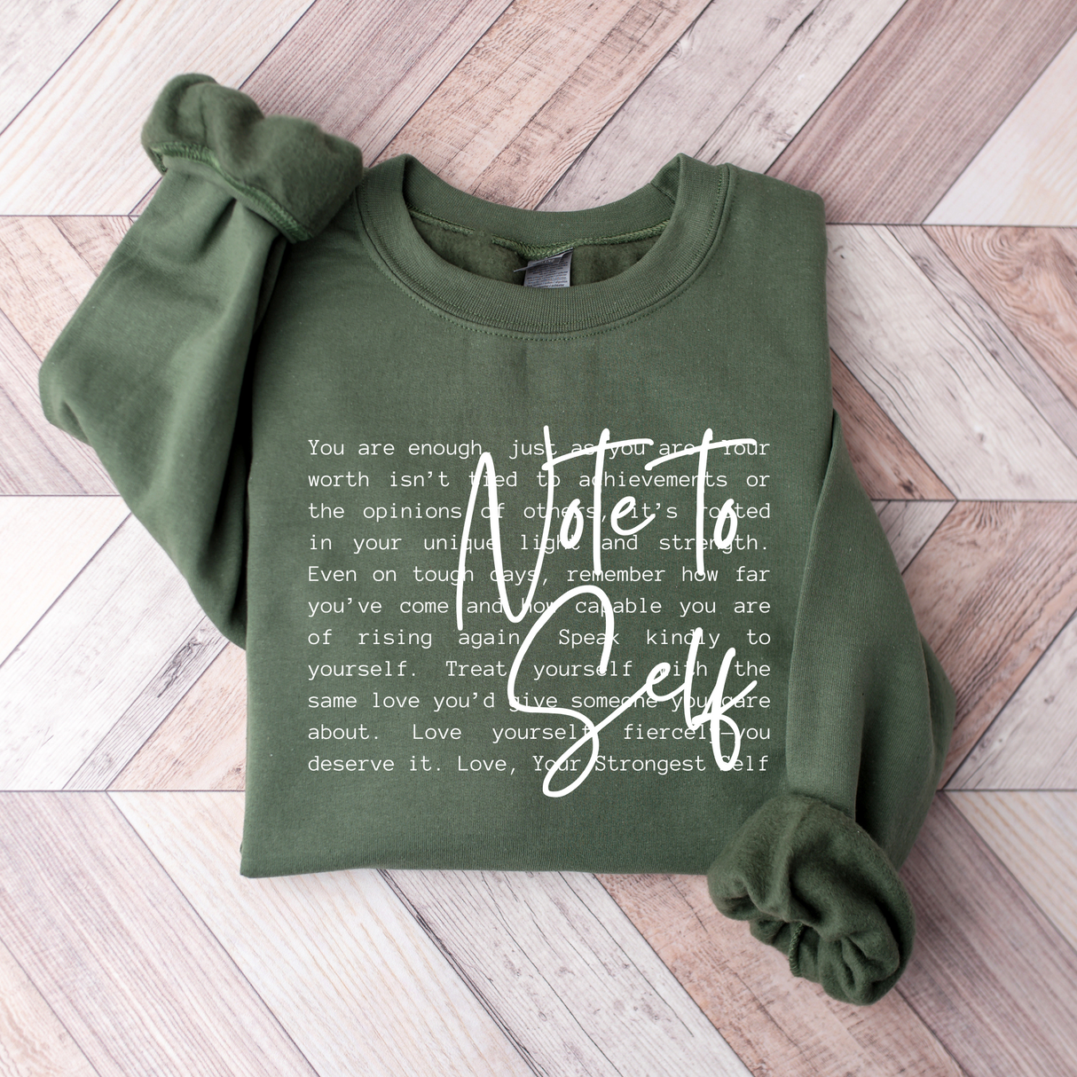 Green sweatshirt with motivational text on a wooden floor