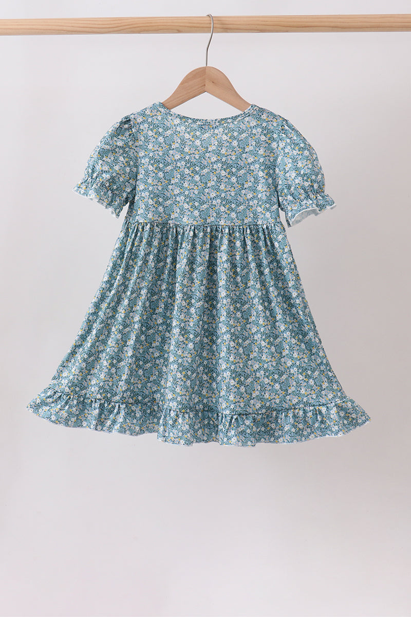 Back view of the blue floral dress with puff sleeves, a gathered waist, and a ruffled hem.