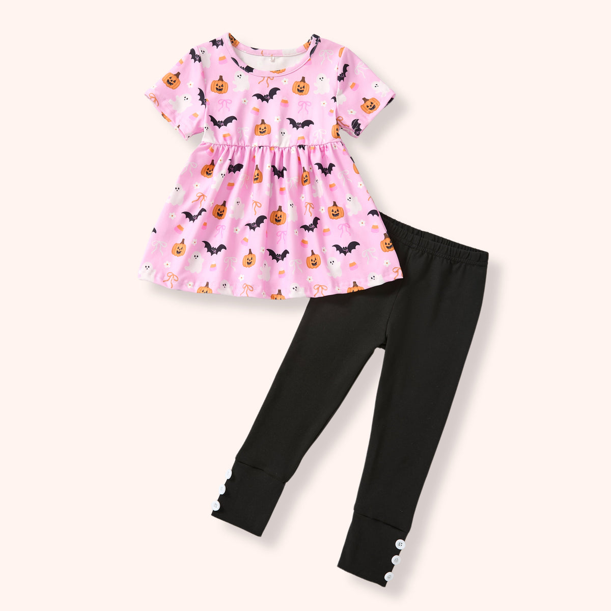 Pink Halloween-themed tunic with pumpkins and bats paired with black leggings on a white background