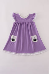 A flat lay of a girls' short-sleeve purple dress featuring white lace trim at the flutter sleeves and hem. The dress has a soft scoop neckline with a polka-dot lining and two front pockets adorned with playful black spider designs on a pale gray background. Made from soft, stretchy milk silk fabric, perfect for Halloween or autumn adventures.