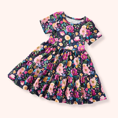 Dark short-sleeve dress with a bold floral print and tiered design, photographed flat on a light background.