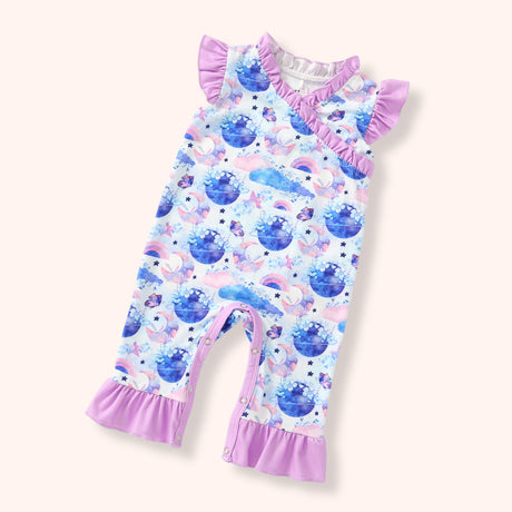 Flat lay of a pastel celestial print onesie with moon, star, cloud, and rainbow motifs, featuring ruffle shoulder detail and lavender ruffle hems.