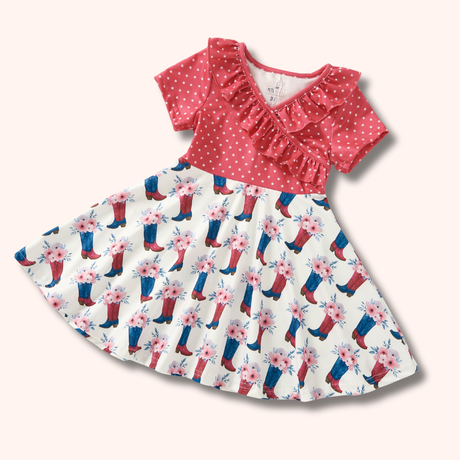 Flat lay of a short-sleeve western-inspired girls dress with a red star print top and a cream skirt featuring cowboy boots with floral accents.
