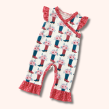 Flat lay of a western-inspired onesie with floral cowboy boot patterning, ruffle shoulder details, red ruffle ankle hems, and snap closure.