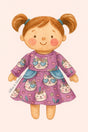 A storybook-style illustration of a smiling doll with pigtails wearing Pete + Lucy’s Purrfectly Cute Doll Dress. The long-sleeve dress features a dusty mauve background with playful kitten faces wearing blue heart-shaped sunglasses and floral crowns, scattered among pink hearts and blossoms. Light blue side pockets add a sweet accent to the twirly skirt.