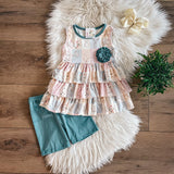 Girls’ patchwork peplum top with teal flower and teal bike shorts, laid flat on faux fur rug.