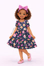 Illustrated girl wearing a dark short-sleeve dress with a bold floral print and tiered design.