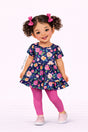 Illustrated girl wearing a dark short-sleeve tunic with a tiered design and bold floral print paired with pink leggings.