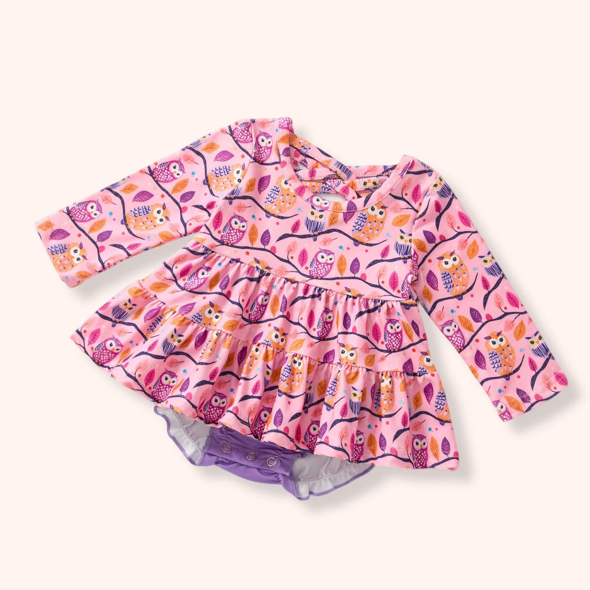 Pink owl-print skirted baby romper with long sleeves and lavender snap bottom.