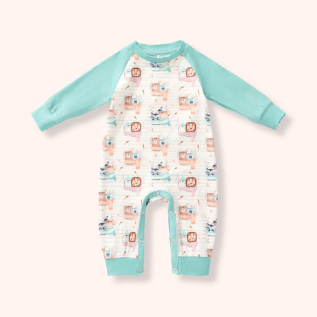 White romper with mint raglan sleeves and cuffs, snap bottom, and a soft woodland animal print on a pale blush background.