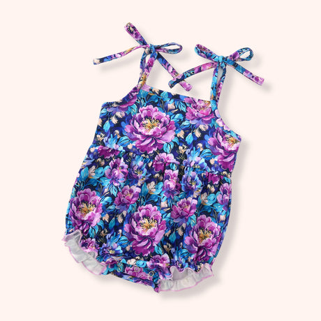 Baby floral bubble romper with purple and blue flowers, tie shoulders, ruffle trim, and snap bottom.