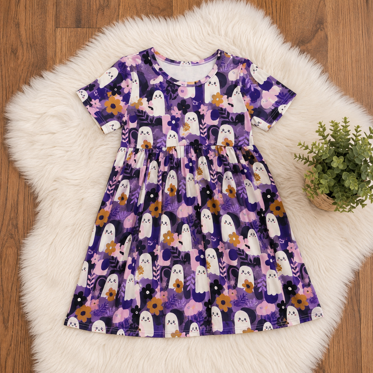 Purple bamboo dress flat lay on white faux fur over wood floor, with white ghosts and purple flowers.
