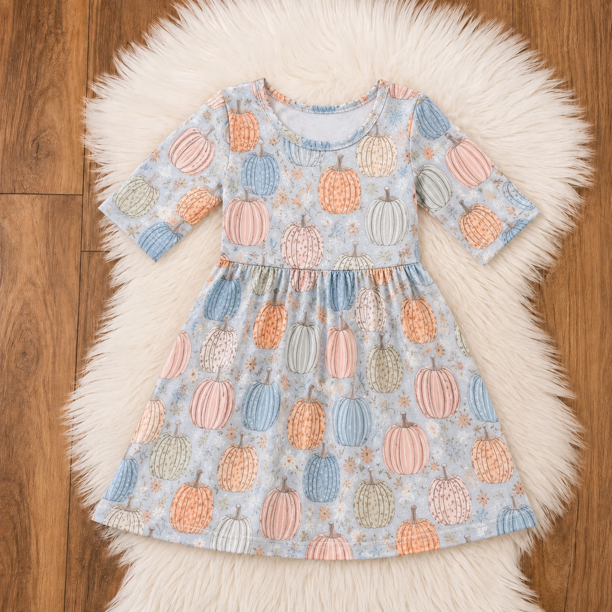 Baby blue bamboo dress flat lay with pastel orange, pink, blue and sage pumpkins on white faux fur.