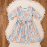 Baby blue bamboo dress flat lay with pastel orange, pink, blue and sage pumpkins on white faux fur.