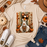 A natural color graphic t-shirt featuring a white goose wearing sunglasses and a bow, surrounded by pumpkins, autumn leaves, and a hotdog, styled in a flat lay with jeans, sneakers, a hat, and fall decor.