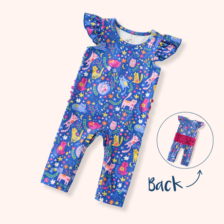 Blue baby romper with colorful cats, flowers, moons and stars, flutter sleeves, cuffed legs and pink ruffle detail across the back.