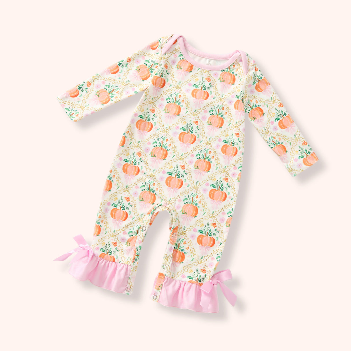 Cream baby footless romper with all-over pumpkin print, pink ruffle hems, side bows and long sleeves.