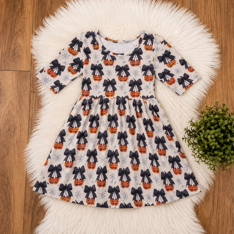Cream Halloween dress with orange jack-o’-lanterns, oversized black bows and gray spiderweb details.