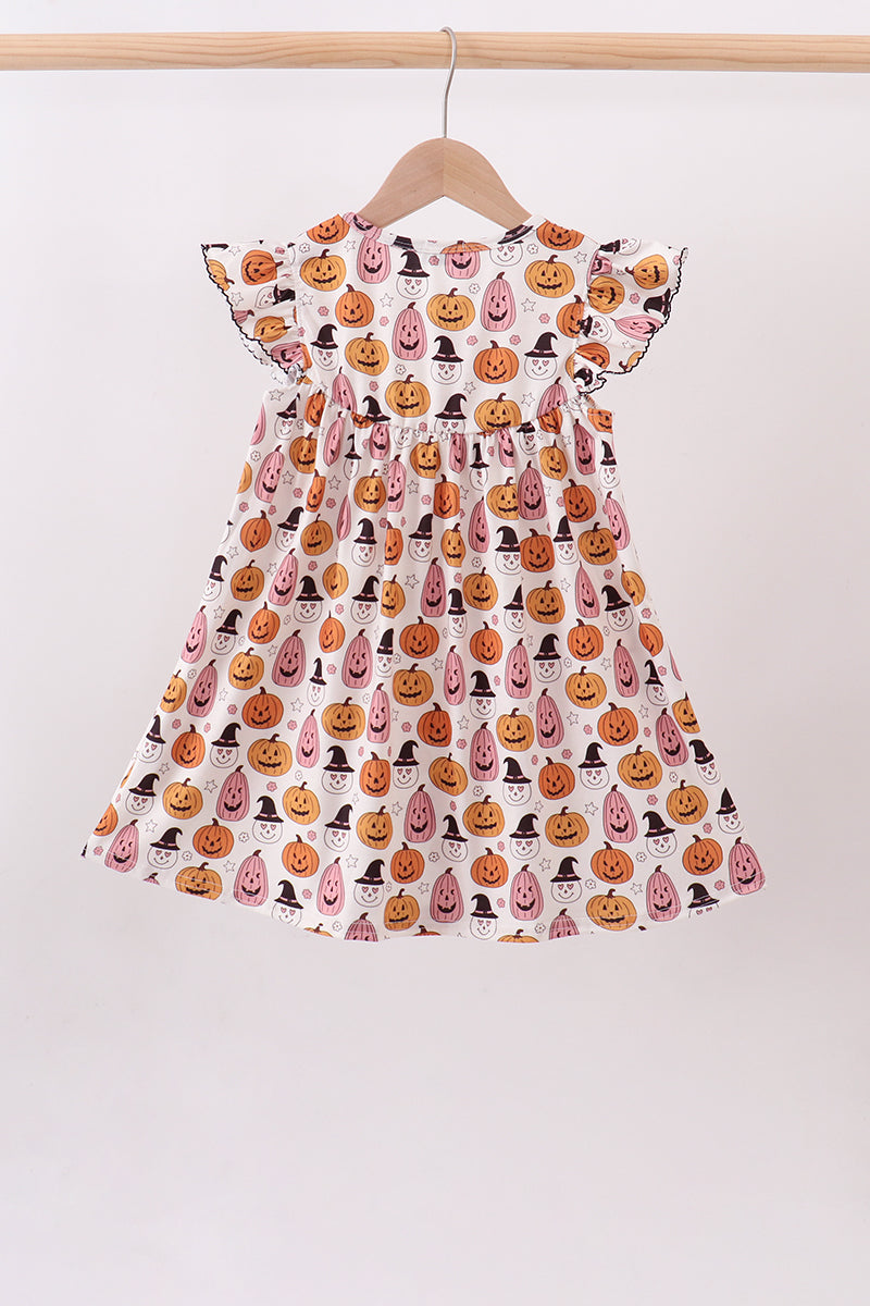 Back view of girls’ ruffle-shoulder dress with orange pumpkins, pink acorns and black witch hats on white.