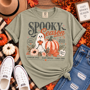 Bay green Comfort Colors tee with a retro “Spooky Season” graphic featuring a smiling ghost, pumpkins, florals, bats and cozy fall sayings.