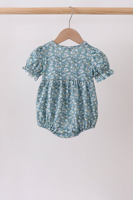 Back view of the baby bubble in a blue floral print with puff sleeves, gathered waist, and elastic leg openings.
