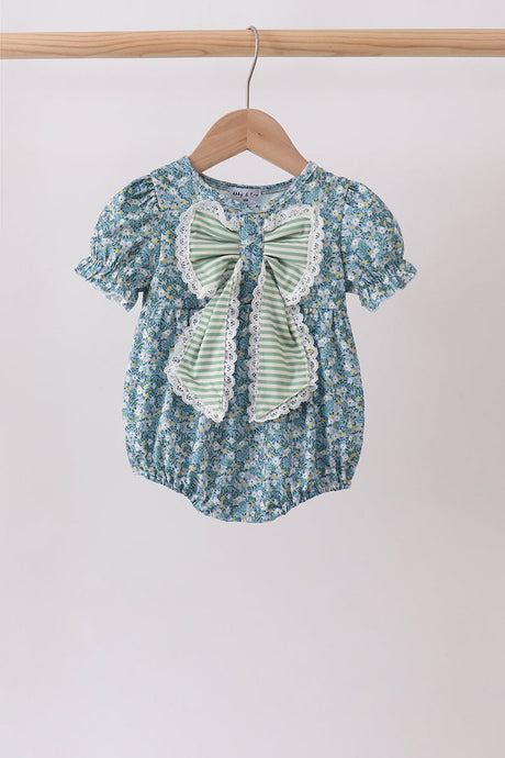 Front view of the baby bubble with a blue floral print, puff sleeves, and a large sage striped bow trimmed in lace.