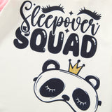 Cream pajama top graphic reading “Sleepover Squad” with sleepy eyelashes and a crowned panda sleep mask.