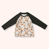 Peach raglan tee with black sleeves and an allover Halloween print of ghosts, pumpkins, candy, webs and “BOO.”