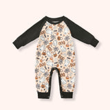 Peach baby raglan romper with black sleeves and a Halloween print of ghosts, candy, pumpkins, webs and “BOO.”