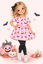 A storybook character with blonde hair and a black bow is wearing a pink short-sleeve dress with a Halloween print of pumpkins, bats, and ghosts, paired with black leggings and white sneakers. She is posed with jack-o'-lanterns and autumn leaves on a soft pink background decorated with floating bats and hearts.