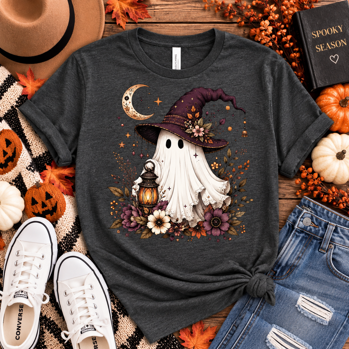 Charcoal tee featuring a whimsical ghost in a plum witch hat holding a glowing lantern, surrounded by a crescent moon, florals, stars and fall foliage.