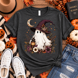 Charcoal tee featuring a whimsical ghost in a plum witch hat holding a glowing lantern, surrounded by a crescent moon, florals, stars and fall foliage.