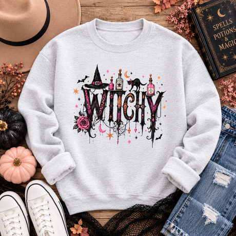 Ash crewneck sweatshirt with a gothic “WITCHY” graphic featuring potion bottles, a black cat, witch hat, rose, bats, moon and stars.
